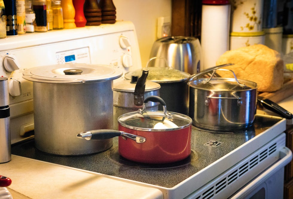 busy stove top with five pots on ceramic surface