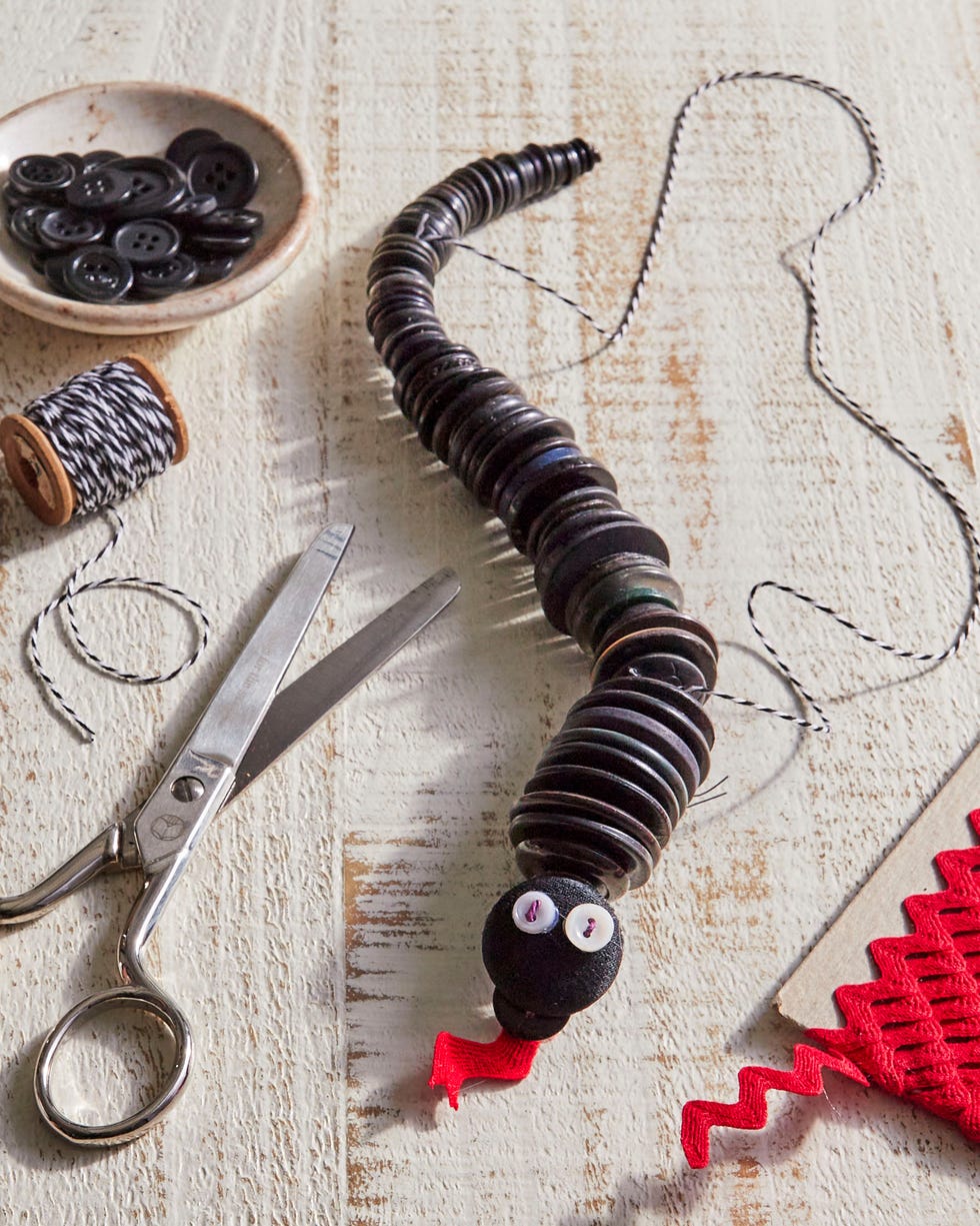 a toy snake made out of black buttons with a red rick rack tongue