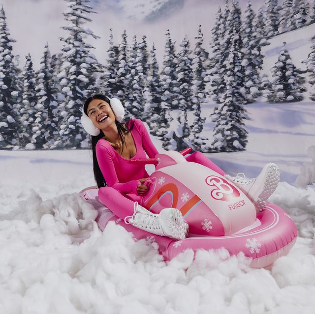 a person sitting on a pink snowmobile in the snow