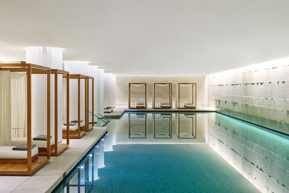 a swimming pool with a glass wall inside the bulgari london hotel