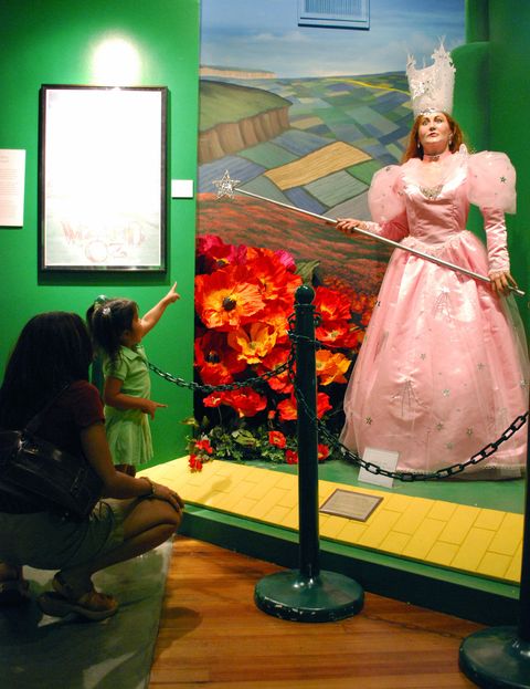 mom and young daughter point to a life sized version of glinda the good witch at the oz museum in kansas