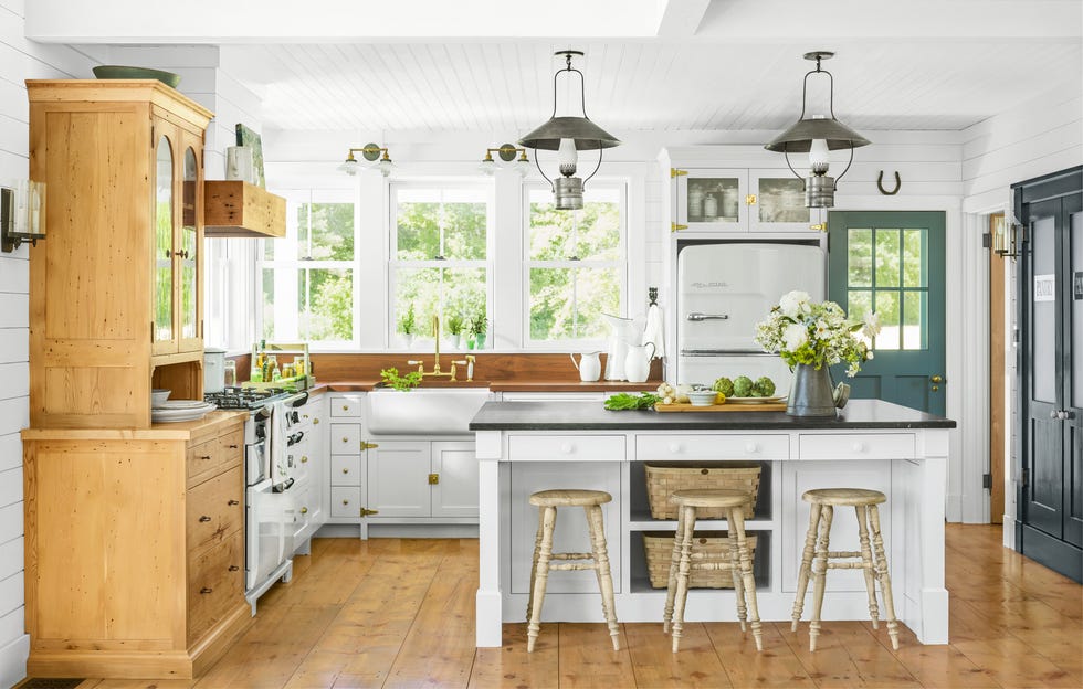 country kitchen with wood floors, white cabinetry, and a white kitchen island with black stone on top