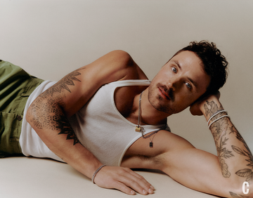 a person lounging with visible tattoos and wearing casual clothing