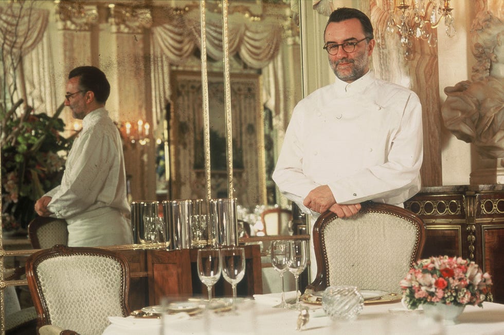 a man standing next to a table with glasses and plates of food