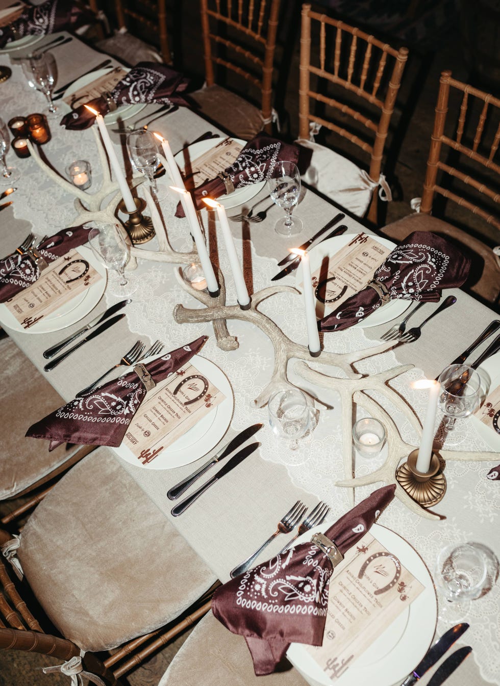 Elegant dinner table setup for an event with lit candles and rustic decor.
