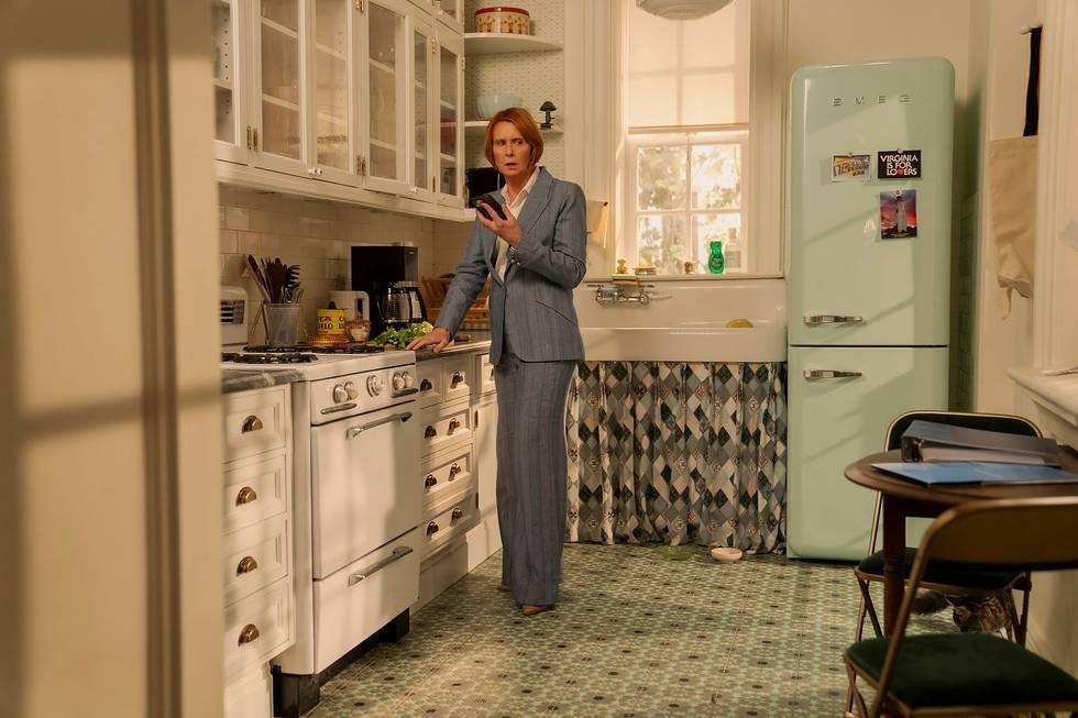 Kitchen setting with a person in formal attire using a smartphone.