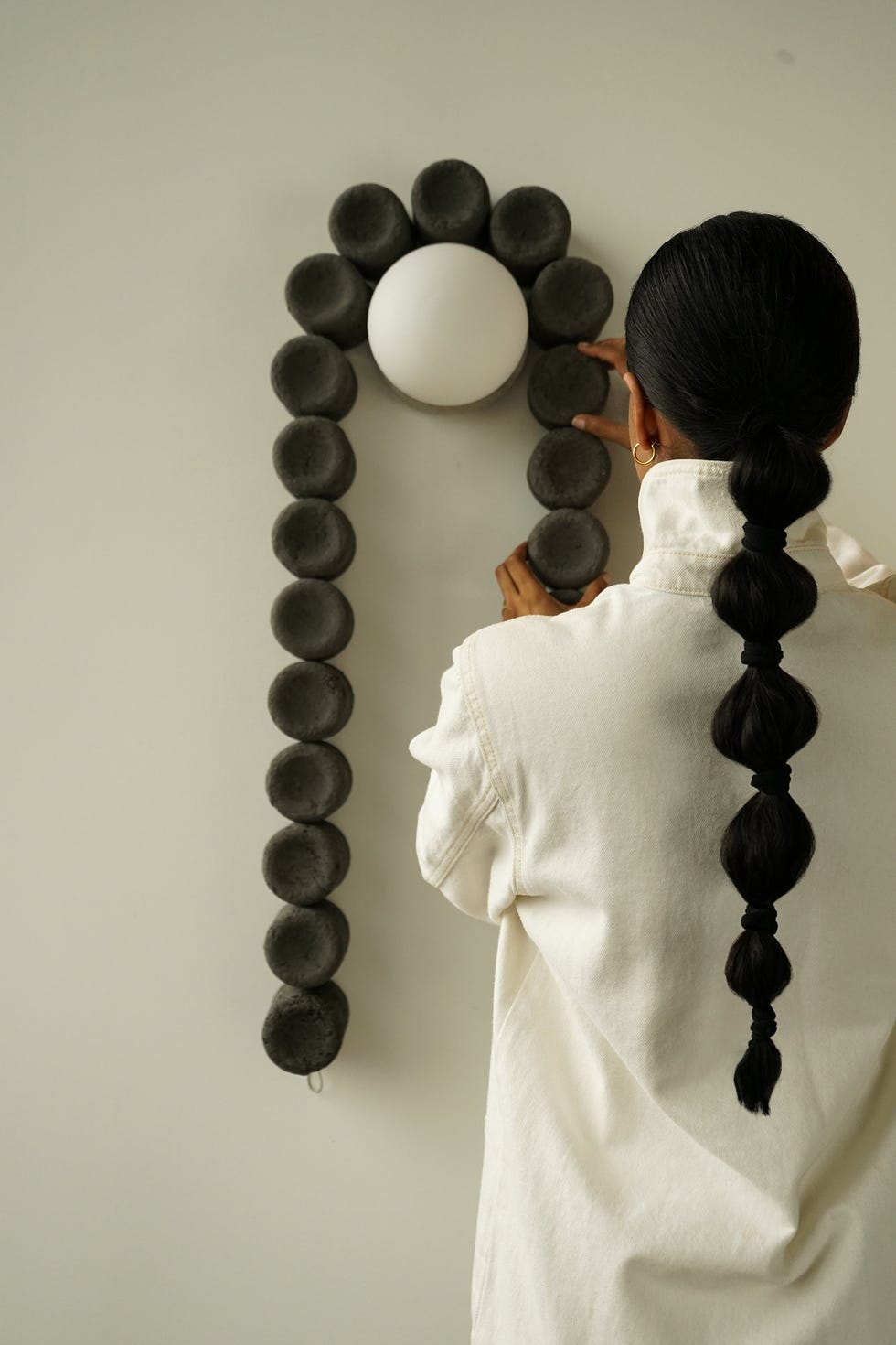 Person arranging spherical wall decor next to a light fixture.