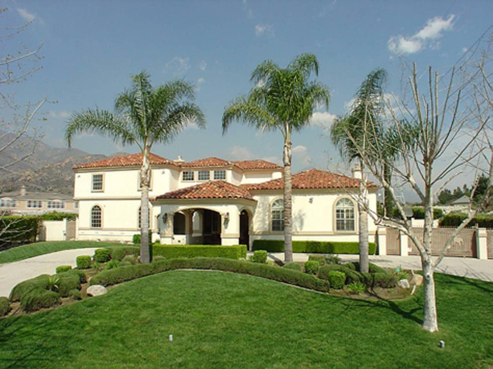 Spanish-style villa with palm trees and well-manicured lawn.