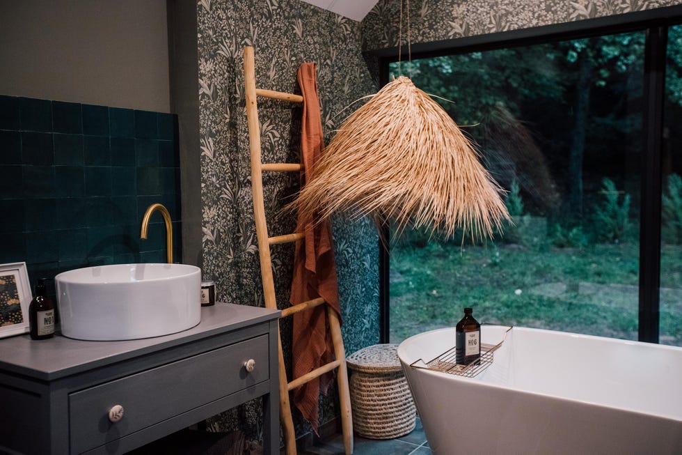 baño con bañera exenta y papel pintado botánico