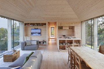 salón comedor de madera con ventanales y sofás modulares en color gris