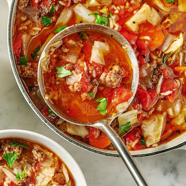 red tomato based soup with cabbage and veggies in a pot