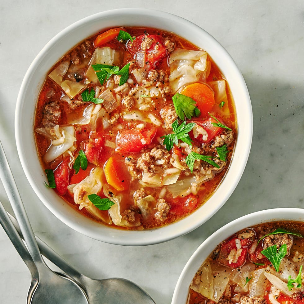 red tomato based soup with cabbage and veggies in a pot