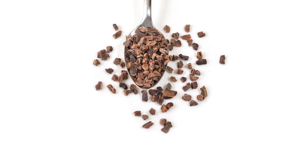cacao nibs in a spoon on white background   isolated