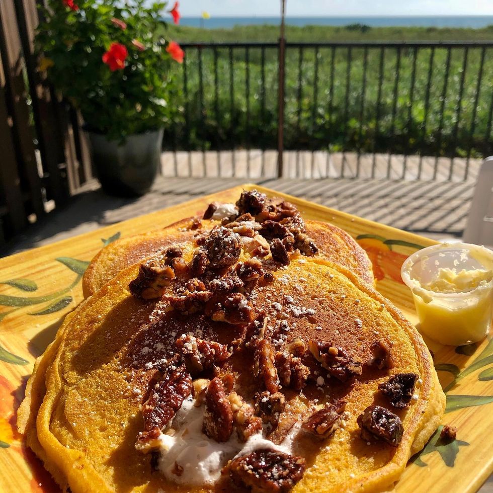 a plate pf pancakes with pecans on them on a table by the ocean