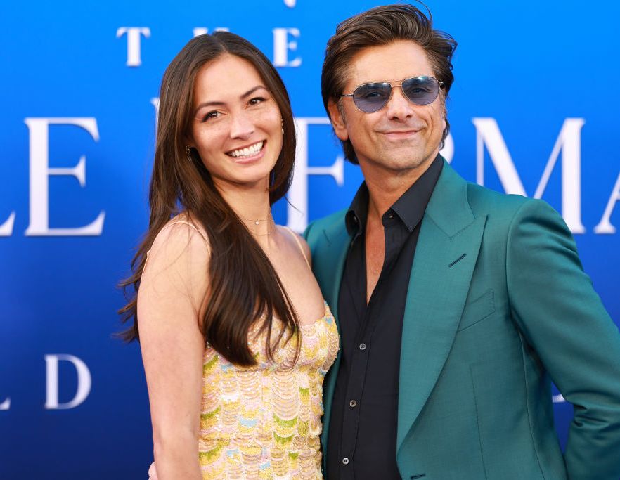 john stamos embracing wife caitlin mchugh for a photo at a film premiere