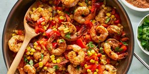 cajun spiced shrimp in a skillet with sliced bell peppers and corn