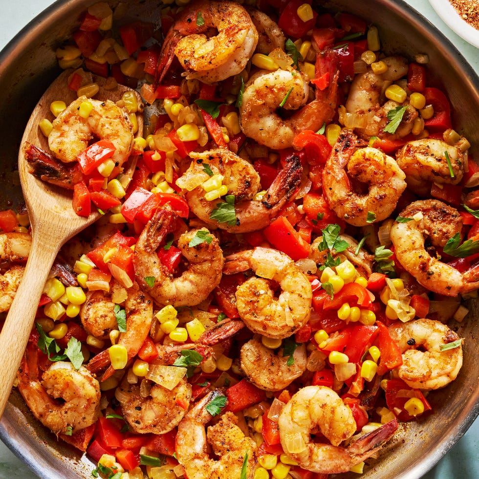 Cajun spiced shrimp in skillet with sliced ​​green peppers and corn