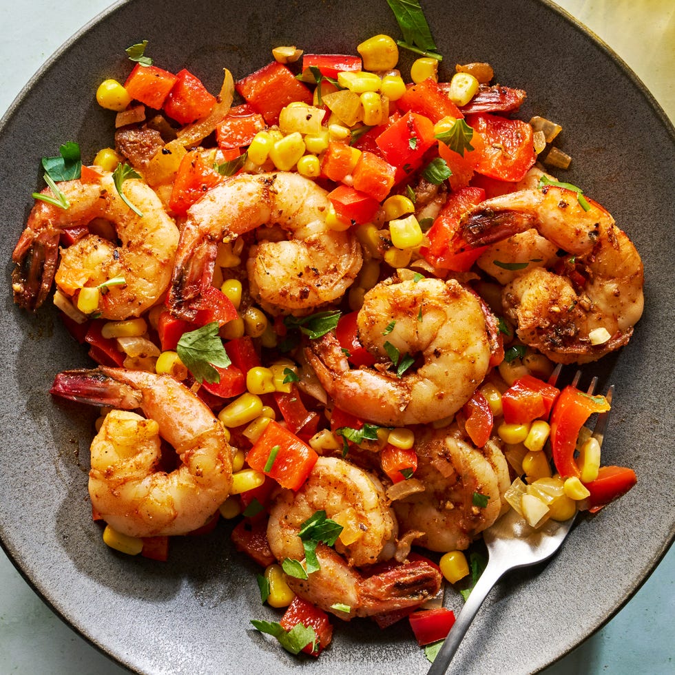 cajun spiced shrimp in a skillet with sliced bell peppers and corn