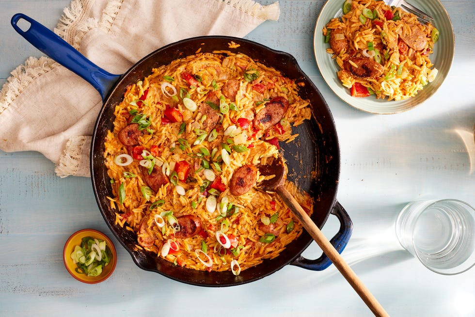 cajun orzo with sausage and green onions in a blue cast iron skillet