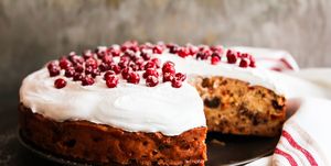 cake with dried fruits and nuts decorated with sweet vanilla meringue and fresh cranberry dusted with icing sugar on a plate, selective focus easter cake image with copy space