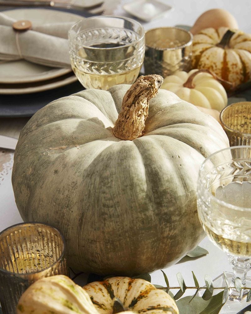 una elegante calabaza encalada acompaña un centro de mesa para halloween