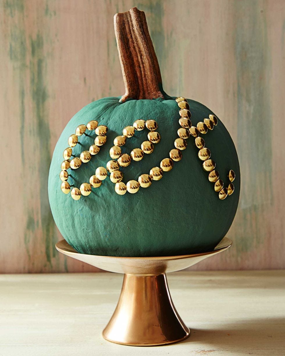 una calabaza pintada de verde y decorada con tachuelas doradas