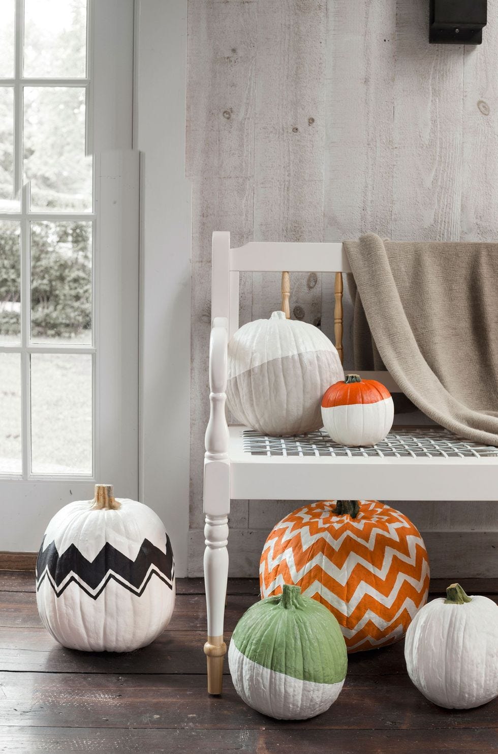 un recibidor decorado con calabazas pintadas de blanco con patrones de colores