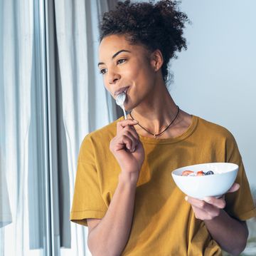 een vrouw eet yoghurt en likt haar lepel af