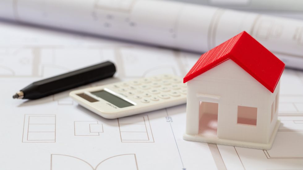 calculator and house model on blueprint background. construction cost concept.