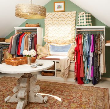 a large closet with lots of hanging clothes and a window seat