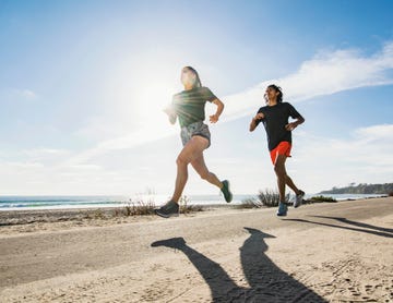 usa, california, dana point, man and woman running together by coastline