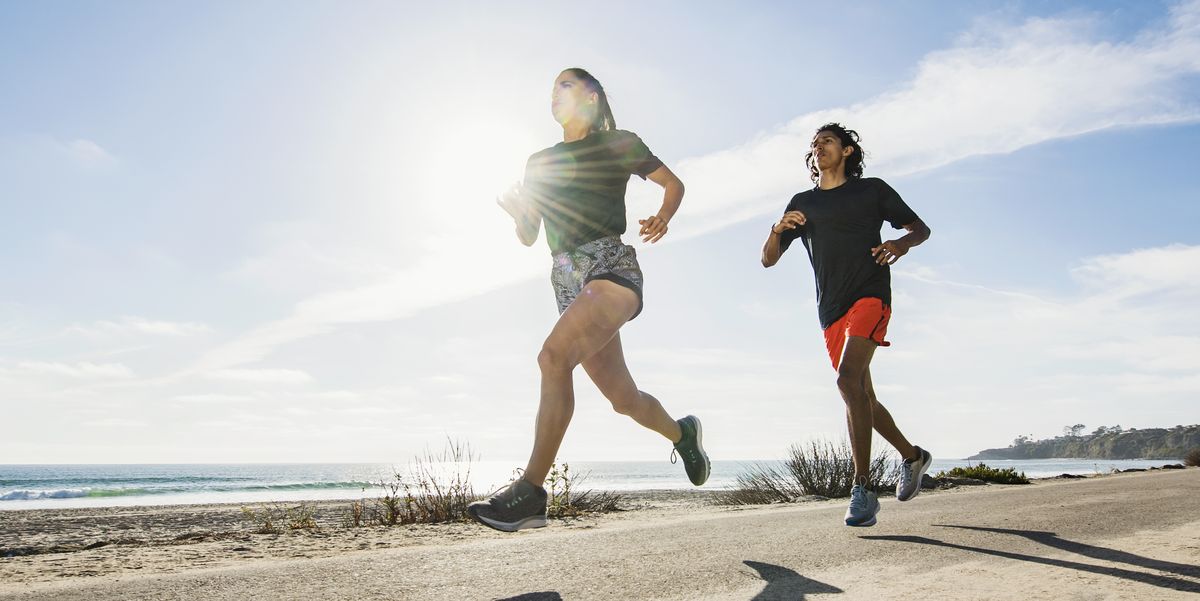 usa, california, dana point, man and woman running together by coastline