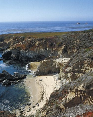 californian coast from overhead with beach surrounded by rocky, rugged landscape