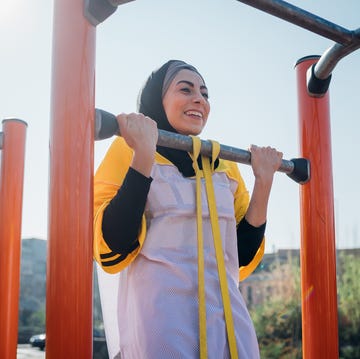 Calisthenics at outdoor gym, young woman doing pull up on exercise equipment calisthenics at outdoor gym, young woman doing pull up on exercise equipment