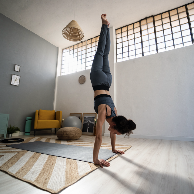 woman does a handstand in living room