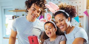 happy parents and child wearing bunny ears, calling the easter bunny's phone number via a smartphone app