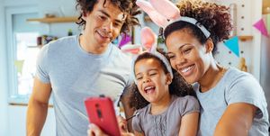 happy parents and child wearing bunny ears, calling the easter bunny's phone number via a smartphone app