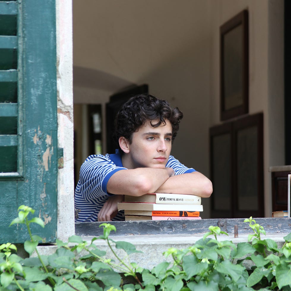 a young individual is resting their arms on a windowsill while looking outside a young individual is resting their arms on a windowsill while looking outside