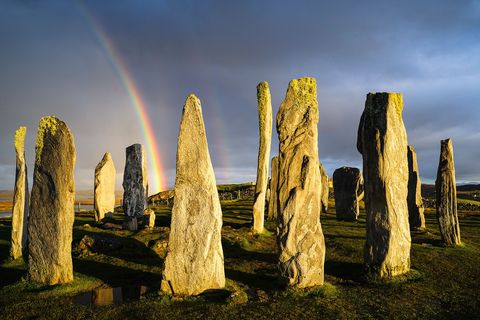 ISLE OF LEWISDe Callanish Standing Stones bij het dorp Callanish op het Isle of Lewis in de Schotse BuitenHebriden was in de bronstijd een brandpunt voor gewijde rituelen Een zeven ton zware centrale monoliet wordt omringd door dertien rechtopstaande stenen terwijl een graf met meerdere kamers is te bewonderen tegen de achtergrond van Loch Roag en de glooiende heuvels van Great Bernera