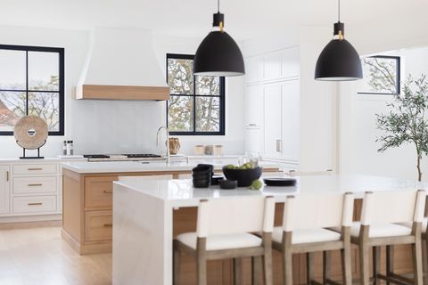 white kitchen, wooden cabinets, white bar chairs, white countertops, black ceiling lamps