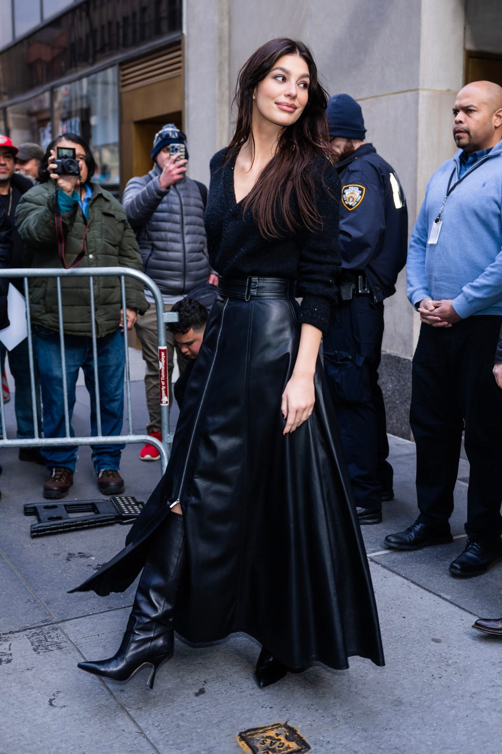 Camila Morrone looks stunning in a black dress with a grey sweater