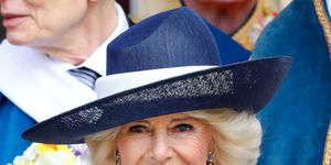 camilla who is now to be known as the queen pictured in a navy hat holding a bunch of flowers