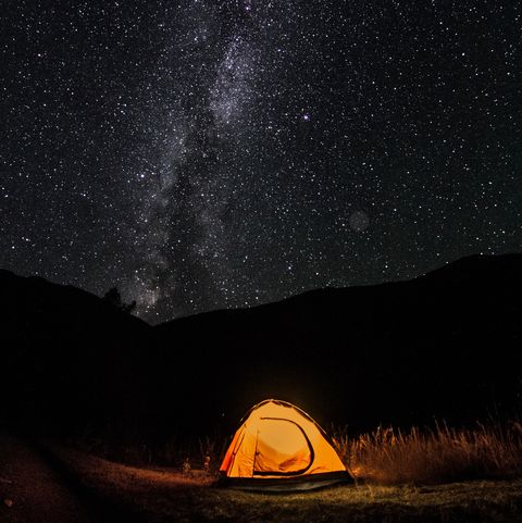 bright orange tent on a background of the starry sky and the milky way