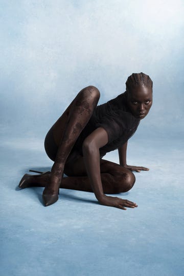 a figure in a unique pose wearing patterned tights and high heels set against a soft blue background