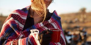 woman wrapping in camping blanket holding mug