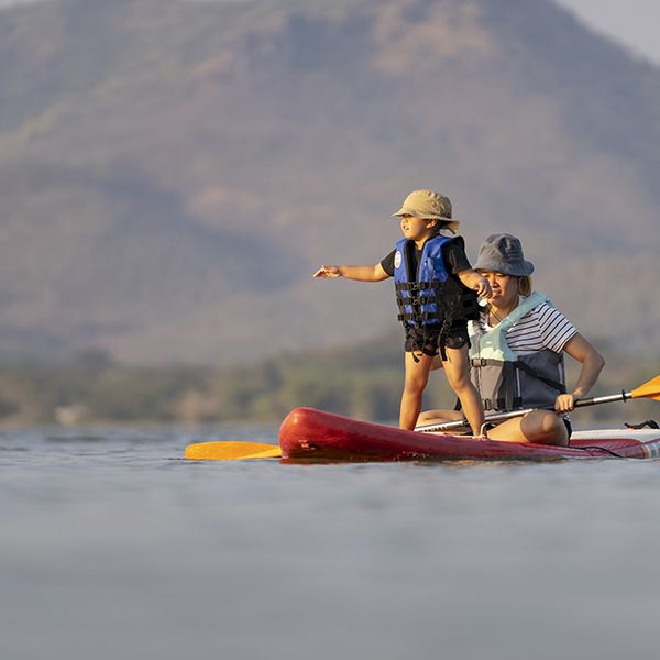 little girl on paddle boarding with mom paddleboarding is a good housekeeping pick for best camping activities