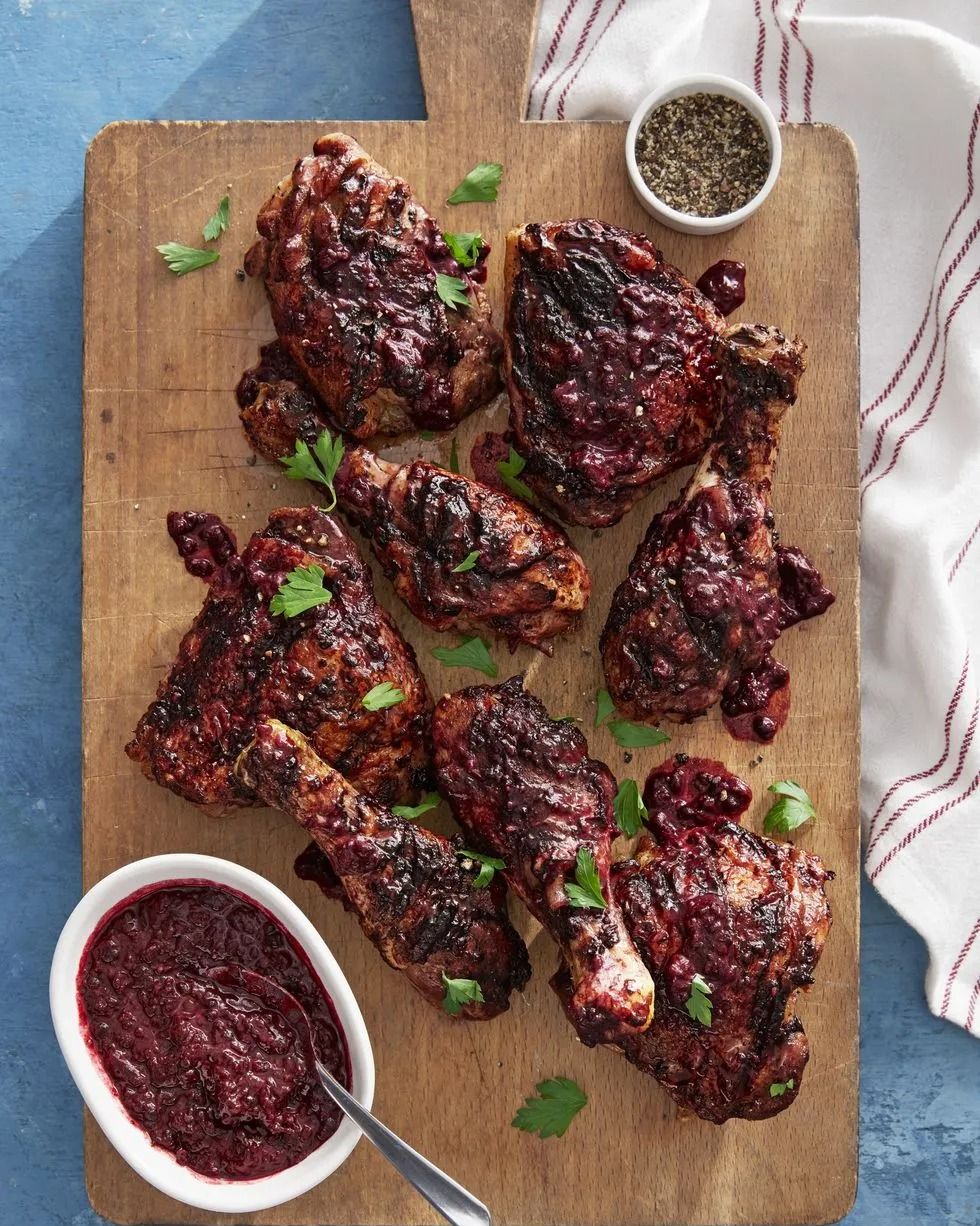 blackberry glazed chicken arranged on a wooden serving board with a small bowl of blackberry glaze