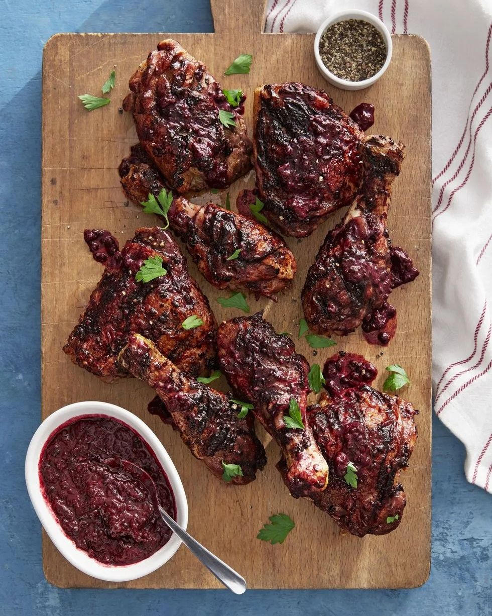 blackberry glazed chicken arranged on a wooden serving board with a small bowl of blackberry glaze