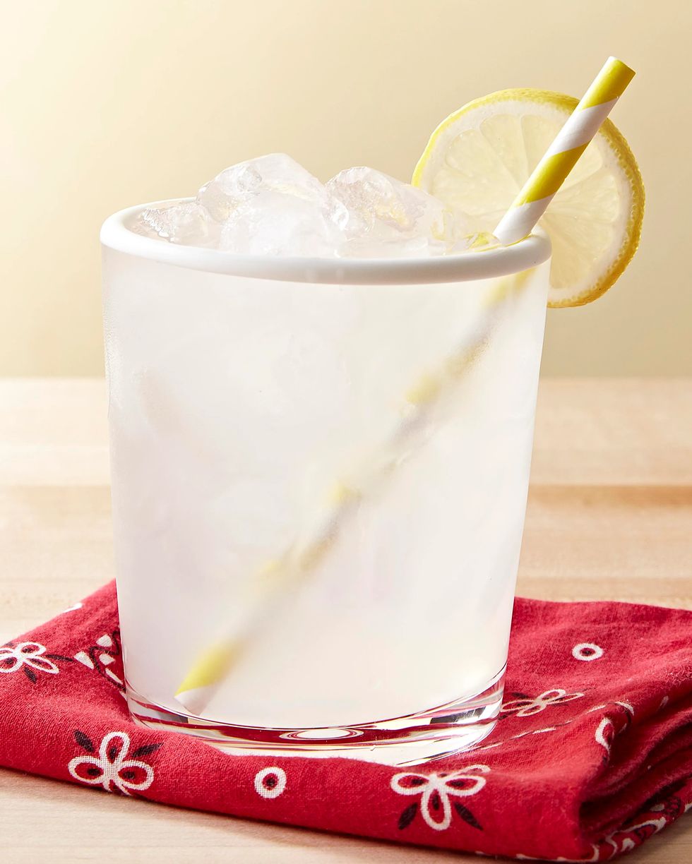 mason jar lemonade in a clear cup with a yellow striped paper straw and a lemon slice for garnish