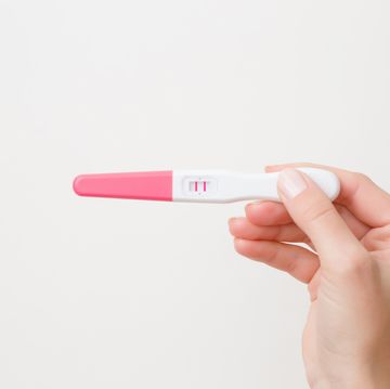 young womans hand holding pregnancy test with a positive result